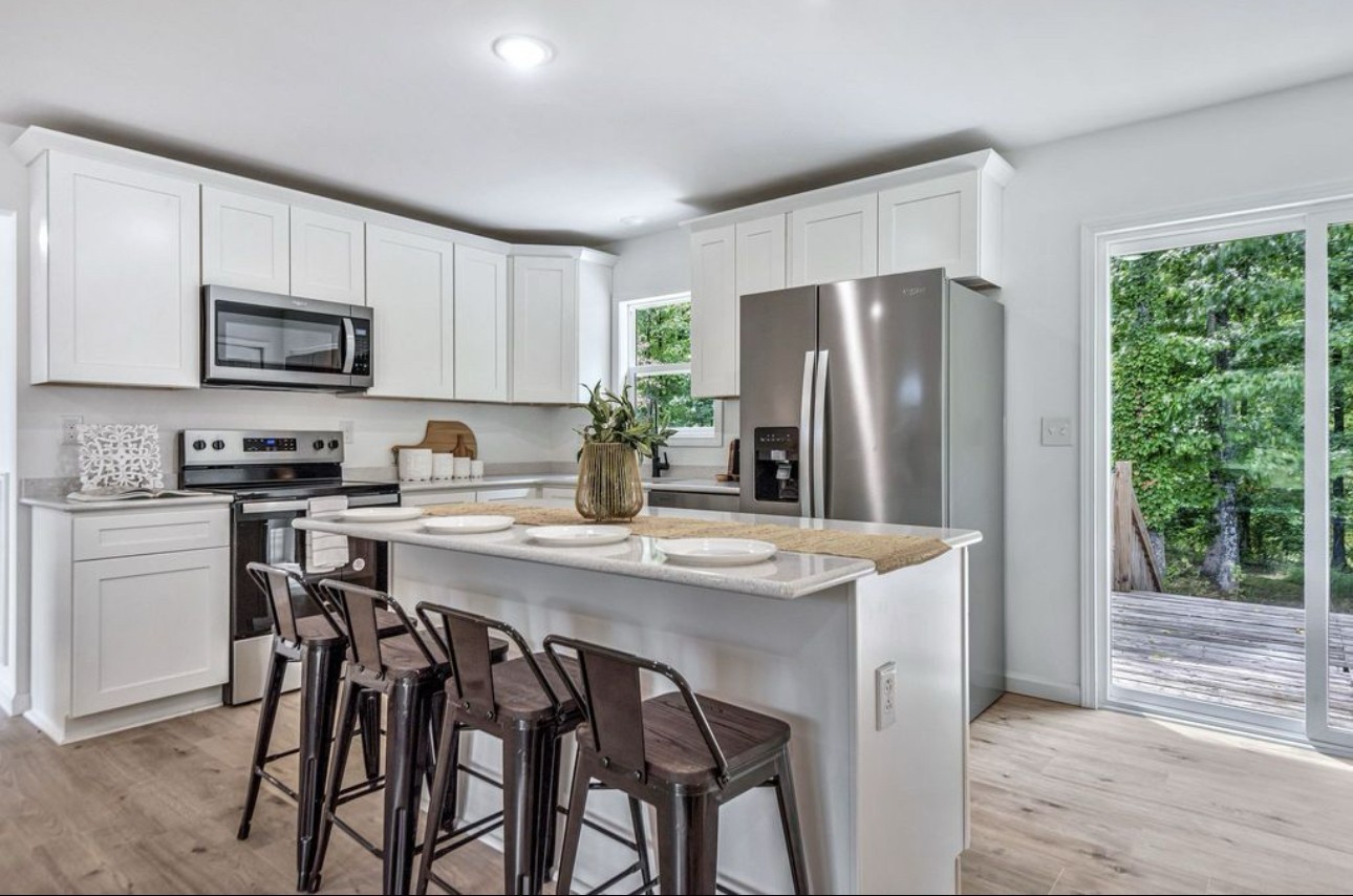 10498 Missionary Ridge Road Bon Aqua, TN 37025 - Photo 14 of 41 a kitchen with stainless steel appliances granite countertop a stove a refrigerator a microwave a sink and white cabinets with wooden floor