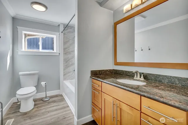 a bathroom with a granite countertop sink and a toilet