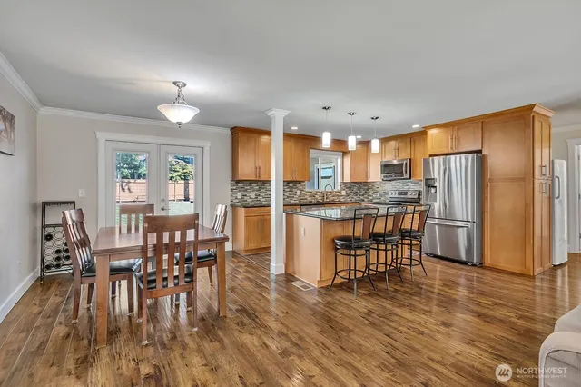 a kitchen with stainless steel appliances a dining table chairs stove refrigerator and cabinets
