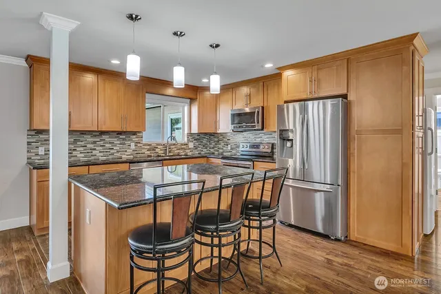 a kitchen with stainless steel appliances granite countertop a refrigerator a sink and a stove