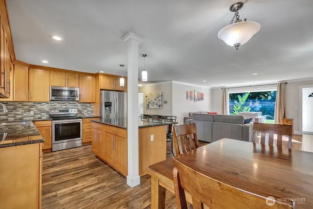 a kitchen with stainless steel appliances granite countertop a stove refrigerator and a view of living room