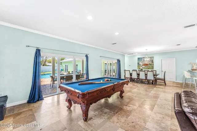a room with furniture pool table and large windows