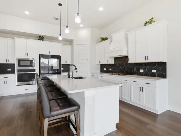 a kitchen with stainless steel appliances a stove a sink a microwave a center island and a cabinets