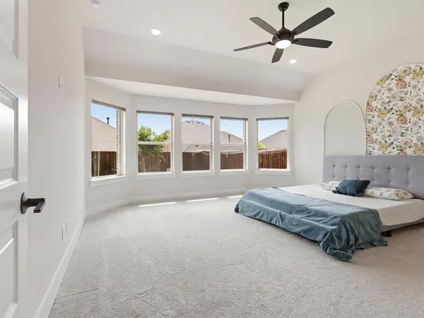 a spacious bedroom with a large bed and a chandelier fan