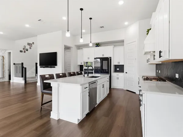 a large white kitchen with lots of counter space a sink appliances and cabinets