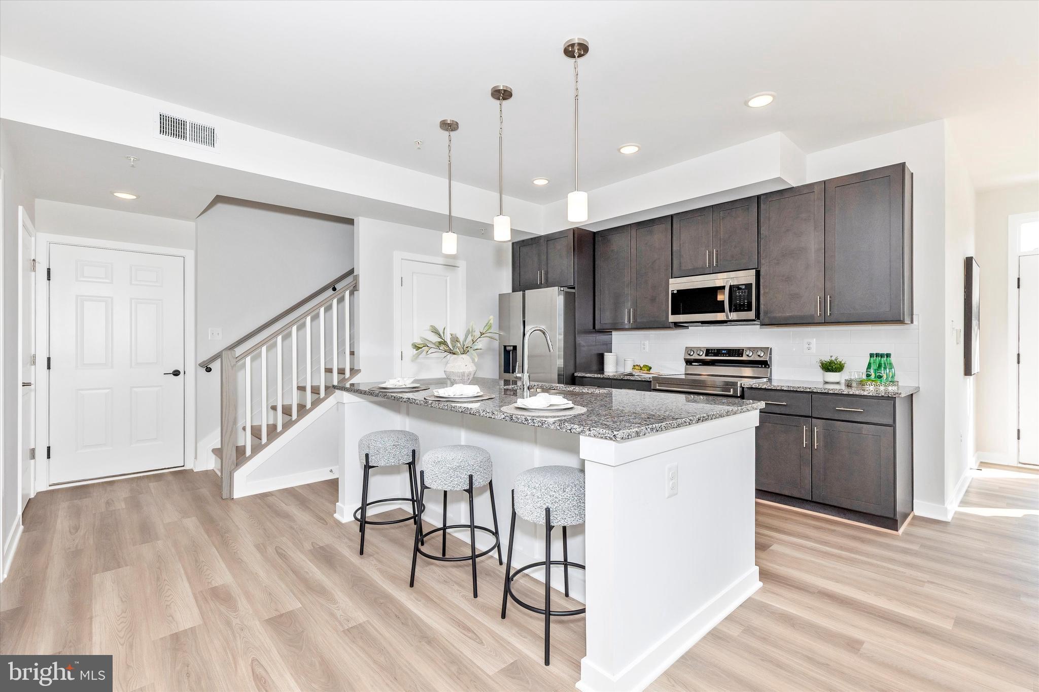 714 Iron Frg Road Frederick, MD 21702 - Photo 15 of 36 a kitchen with kitchen island granite countertop a stove top oven a sink dishwasher a dining table and chairs with wooden floor
