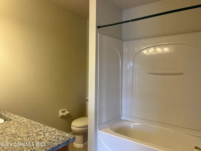 a bathroom with a granite countertop toilet and a sink