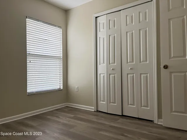 an empty room with wooden floor and closet area