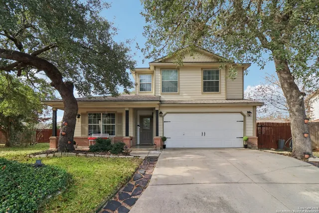 a view of a house with a yard and large tree