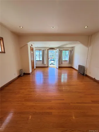 a view of an empty room with window and wooden floor