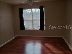 a view of empty room with wooden floor and fan