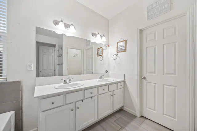 a spacious bathroom with a double vanity sink a mirror and a