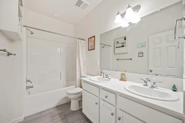 a bathroom with a double vanity sink double mirror bathtub shower and toilet