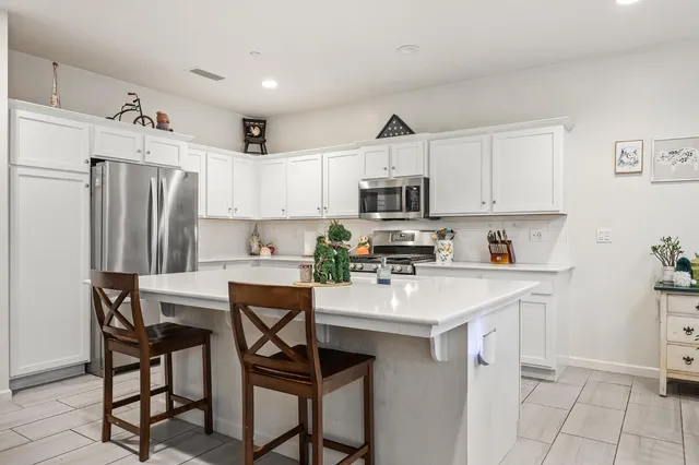 a kitchen with stainless steel appliances a table chairs refrigerator and a sink