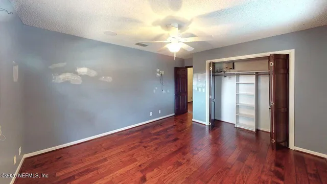 an empty room with wooden floor and a ceiling fan