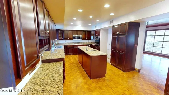 a kitchen with stainless steel appliances granite countertop wooden cabinets a sink and a stove