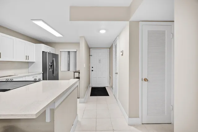 a large white kitchen with a refrigerator a stove top oven and cabinets