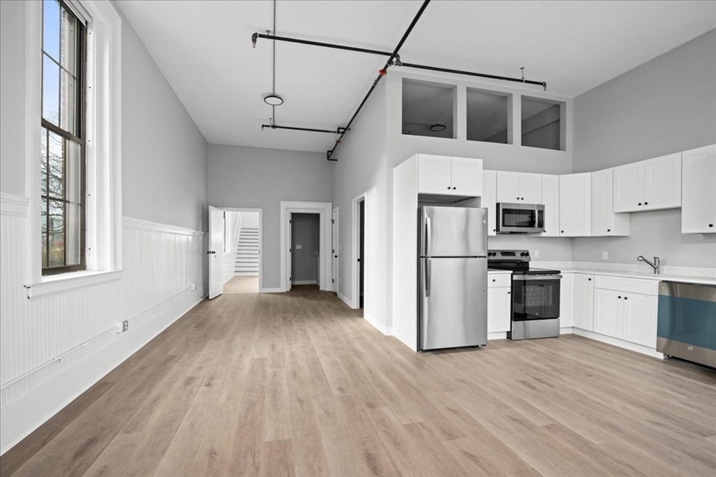 22 Waverly Street Worcester, MA 01604 - Photo 13 of 41 a kitchen with stainless steel appliances granite countertop a refrigerator a stove a sink dishwasher and white cabinets with wooden floor