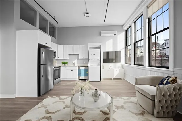 a living room with stainless steel appliances furniture and a kitchen view