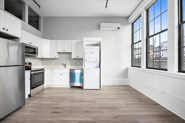 a kitchen with granite countertop a refrigerator a sink dishwasher and a stove with wooden floors