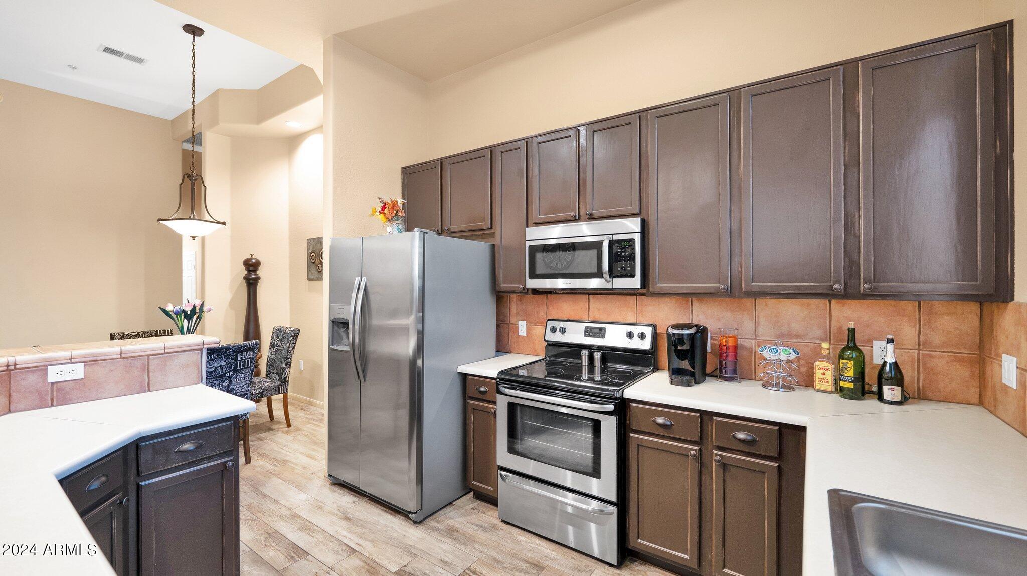 8245 East Bell Road, Unit 207 Scottsdale, AZ 85260 - Photo 11 of 33 a kitchen with stainless steel appliances wooden cabinets a sink and a stove