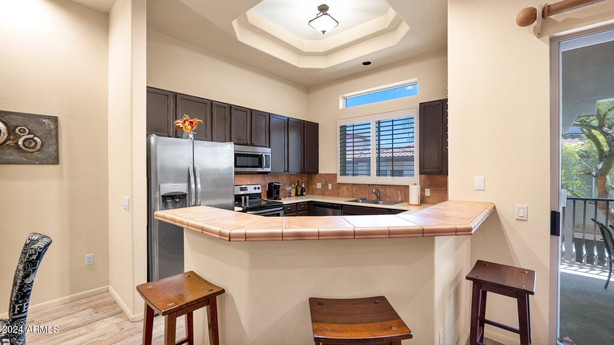 8245 East Bell Road, Unit 207 Scottsdale, AZ 85260 - Photo 8 of 33 a kitchen with stainless steel appliances granite countertop a sink a stove a refrigerator a dining table and chairs with wooden floor