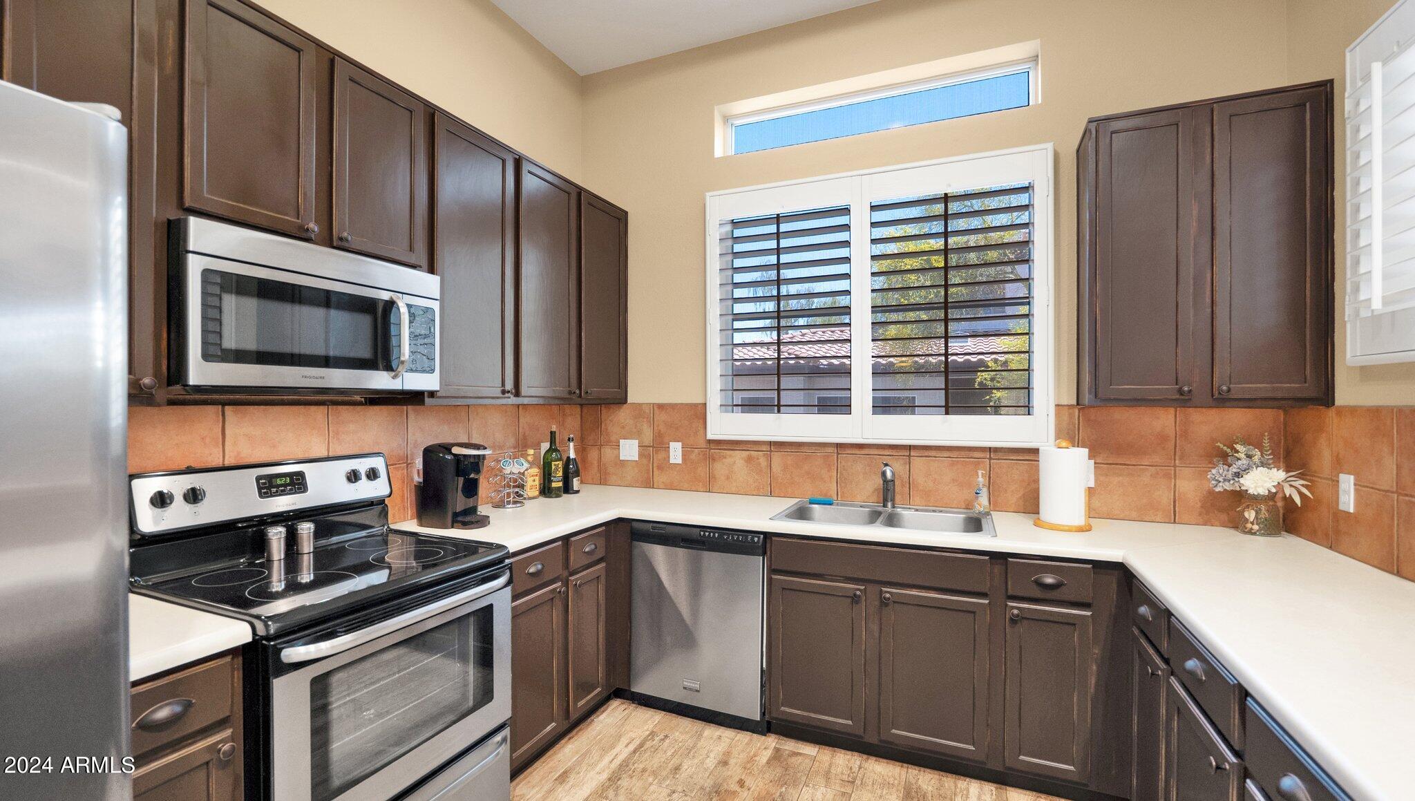 8245 East Bell Road, Unit 207 Scottsdale, AZ 85260 - Photo 9 of 33 a kitchen with stainless steel appliances wooden cabinets stove and a sink