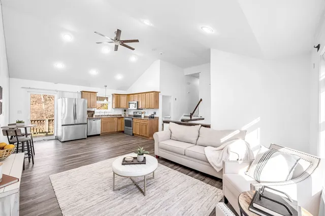 a living room with furniture kitchen view and a wooden floor