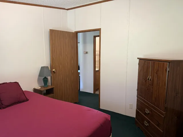 a bedroom with a bed and a lamp on the dresser