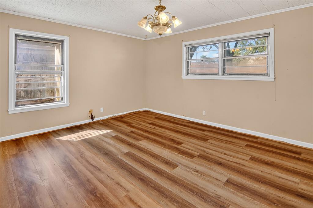 904 Northwest 7th Avenue Mineral Wells, TX 76067 - Photo 17 of 36 Empty room featuring crown molding, light wood-type flooring, and a chandelier