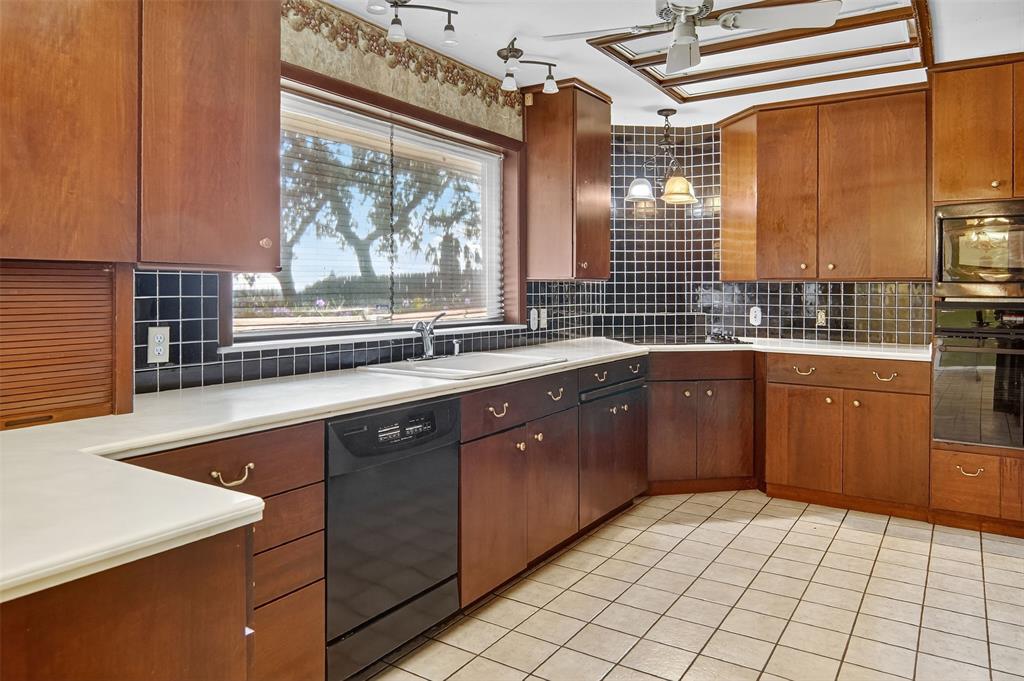 904 Northwest 7th Avenue Mineral Wells, TX 76067 - Photo 6 of 36 Kitchen featuring black appliances, light tile patterned flooring, tasteful backsplash, and brown cabinetry