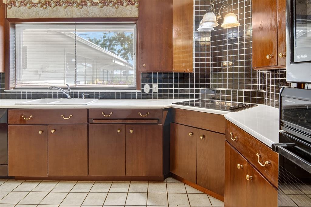 904 Northwest 7th Avenue Mineral Wells, TX 76067 - Photo 7 of 36 Kitchen featuring decorative backsplash, light tile patterned floors, decorative light fixtures, black appliances, and brown cabinets