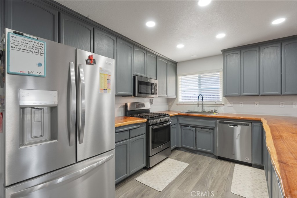 175 South 7th Street Shandon, CA 93461 - Photo 3 of 7 a kitchen with stainless steel appliances granite countertop a refrigerator a sink dishwasher a stove and a microwave oven on the blue kitchen countertops with wooden floor