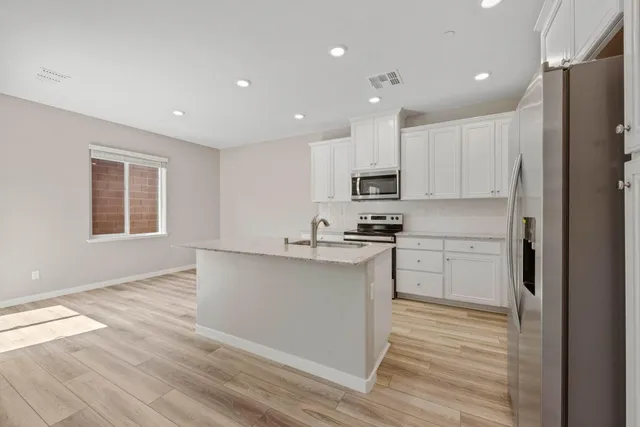 a kitchen with stainless steel appliances granite countertop a refrigerator sink and white cabinets