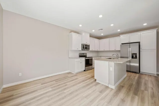 a kitchen with a refrigerator and white cabinets