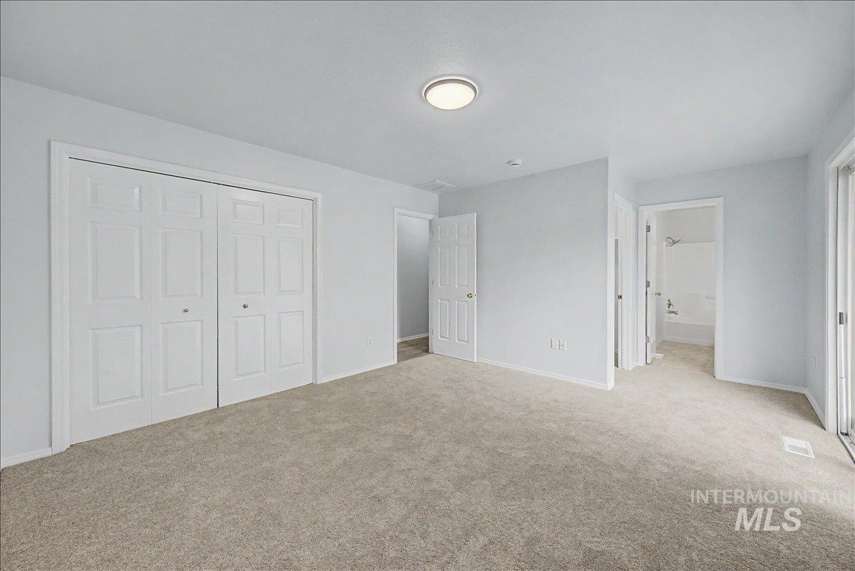 2501 West Hill Road Boise, ID 83702 - Photo 21 of 31 Unfurnished bedroom featuring a closet, light carpet, and connected bathroom