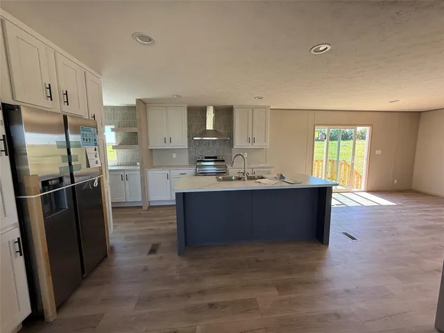 a kitchen with stainless steel appliances kitchen island granite countertop a refrigerator and a sink