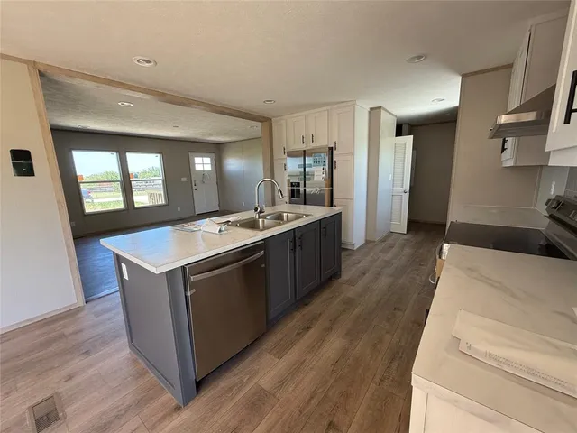 a large kitchen with stainless steel appliances granite countertop a large counter top and wooden floors