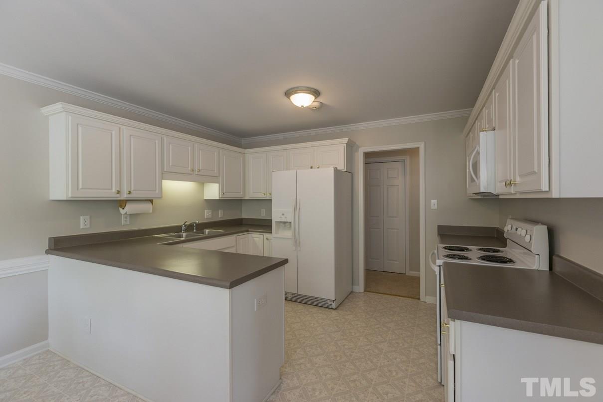 826 Shackleton Road Apex, NC 27502 - Photo 5 of 24 a kitchen with granite countertop a sink stove and refrigerator