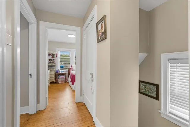 a hallway with wooden floor a bedroom and a bed