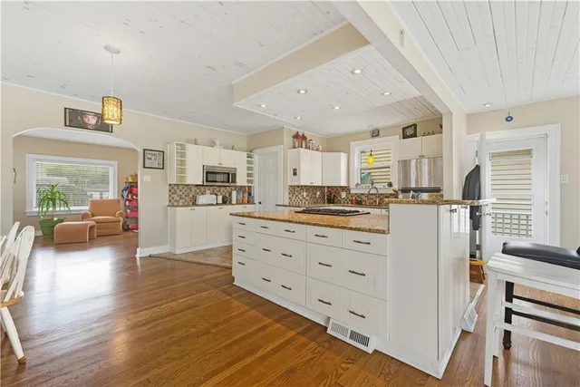 a kitchen with stainless steel appliances kitchen island granite countertop a refrigerator and cabinets