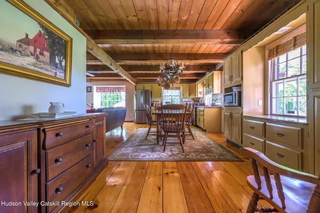 a dining room with wooden floors and a view of the kitchen
