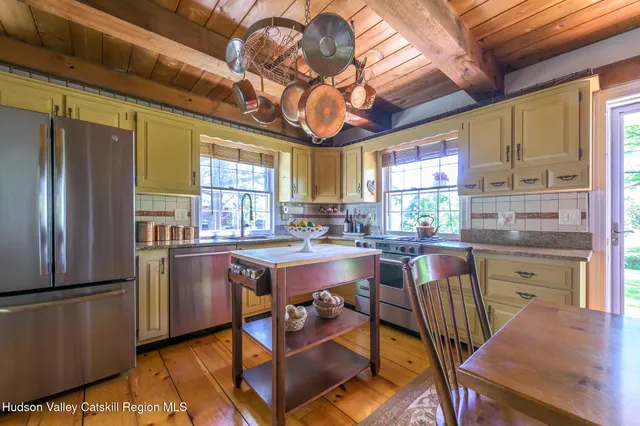 a kitchen with stainless steel appliances granite countertop a refrigerator a sink dishwasher a stove and a dining table with wooden floor