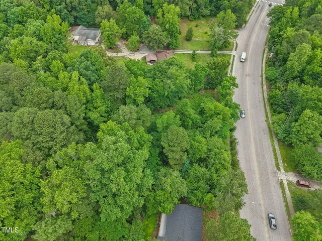 an aerial view of residential house with outdoor space and trees all around