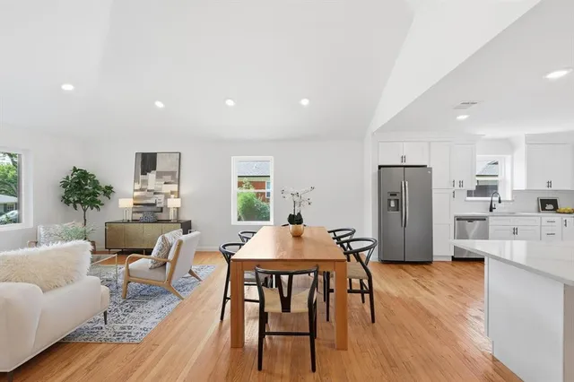 a living room with stainless steel appliances furniture dining table and wooden floor