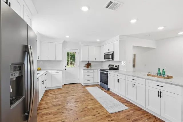 a large kitchen with white cabinets and stainless steel appliances