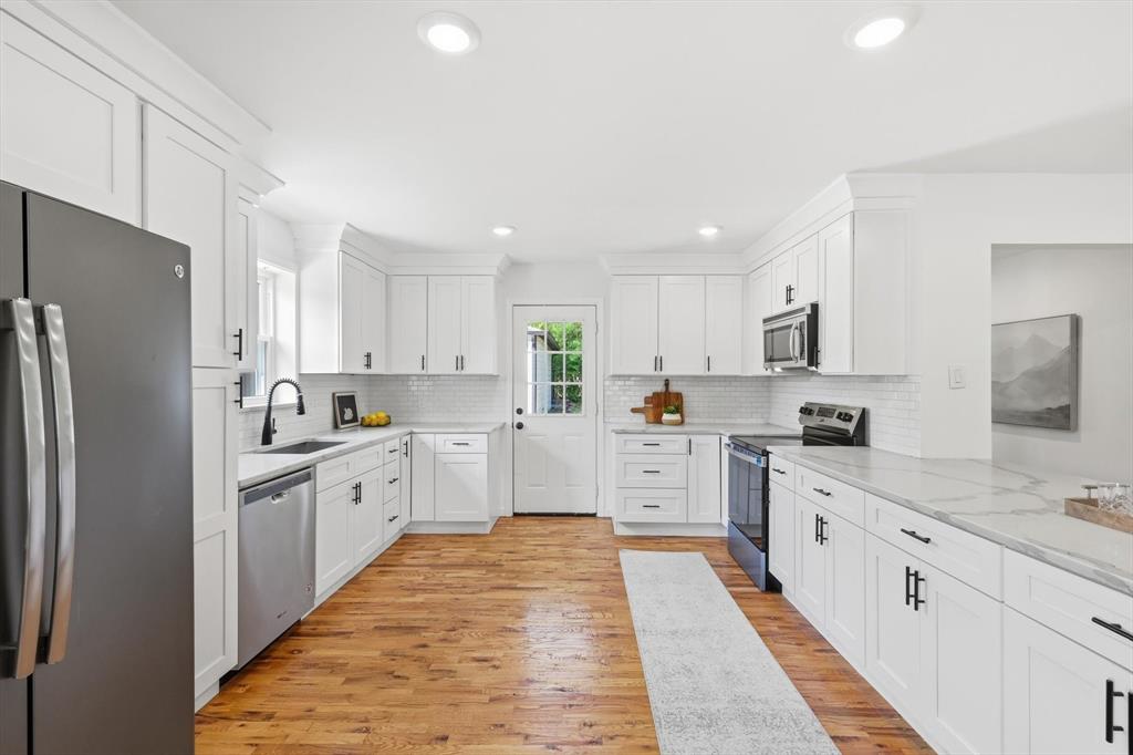 6811 Patrick Drive Dallas, TX 75214 - Photo 18 of 40 Kitchen with white cabinetry, stainless steel appliances, light stone counters, light wood finished floors, and recessed lighting