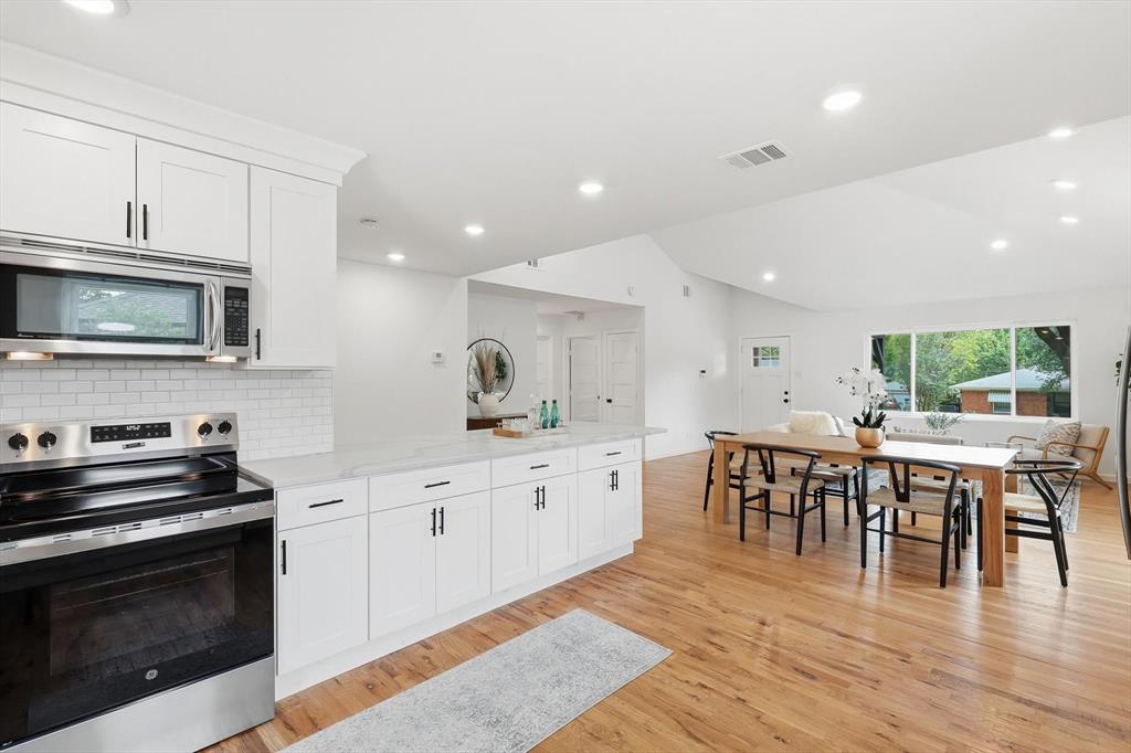 6811 Patrick Drive Dallas, TX 75214 - Photo 21 of 40 Kitchen with appliances with stainless steel finishes, white cabinetry, vaulted ceiling, recessed lighting, and light wood-style floors
