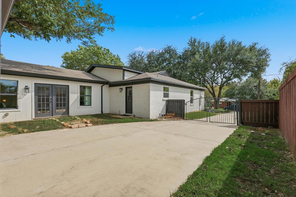 6811 Patrick Drive Dallas, TX 75214 - Photo 38 of 40 View of side of property featuring brick siding, a gate, driveway, and french doors