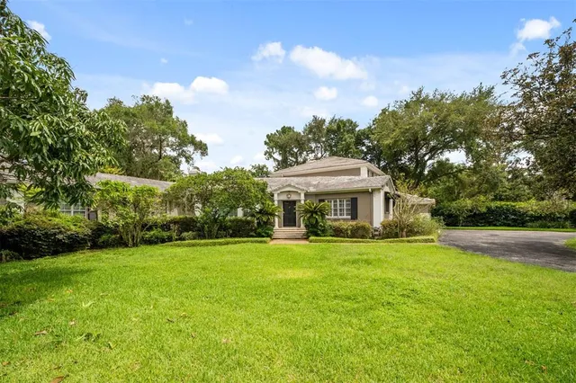 a view of a house with a big yard and large trees